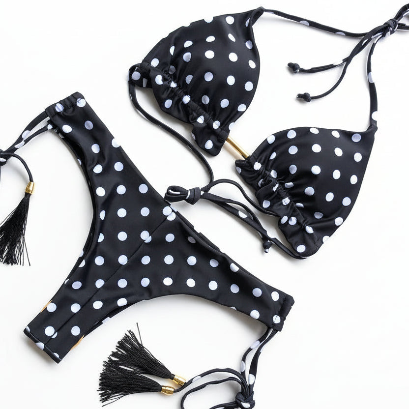 Black bikini set with white polka dots and tassels on a white background