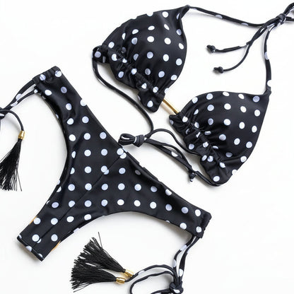 Black bikini set with white polka dots and tassels on a white background