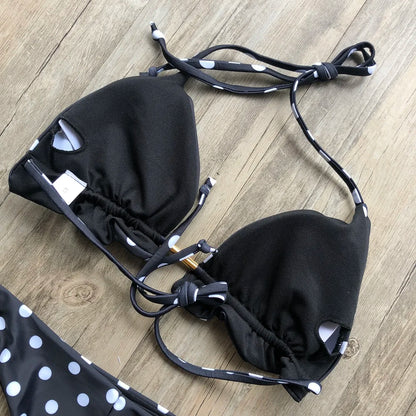 Black bikini with white polka dots on a wooden surface