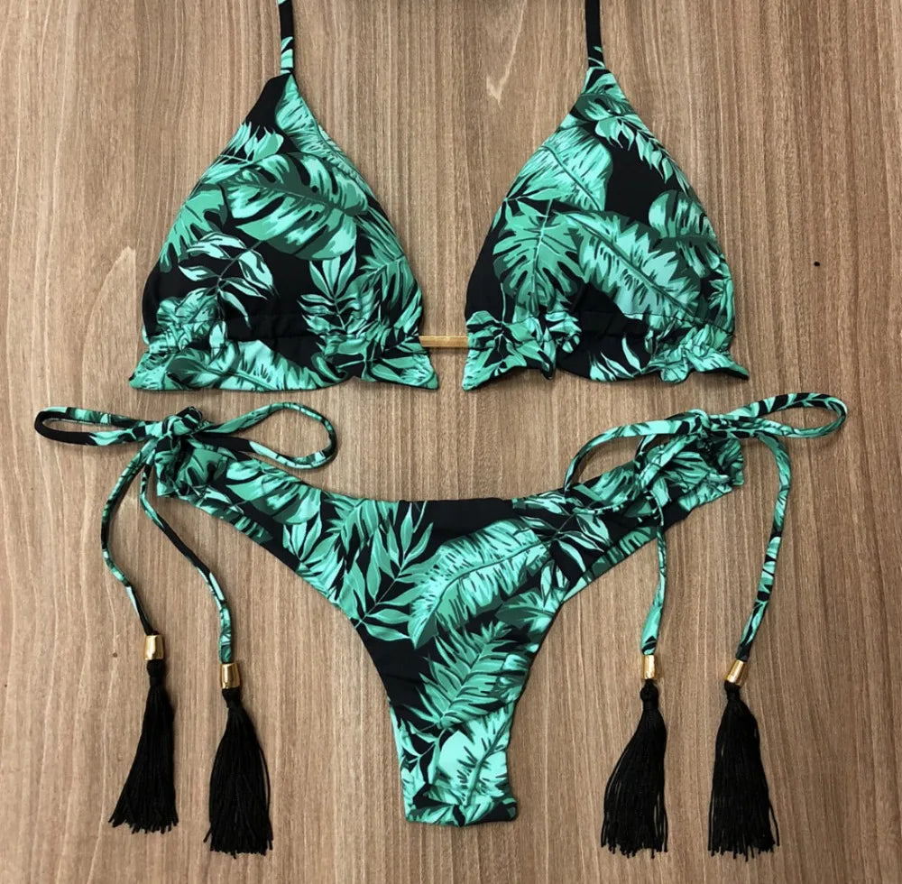 Tropical leaf patterned bikini set with tassels on a wooden background
