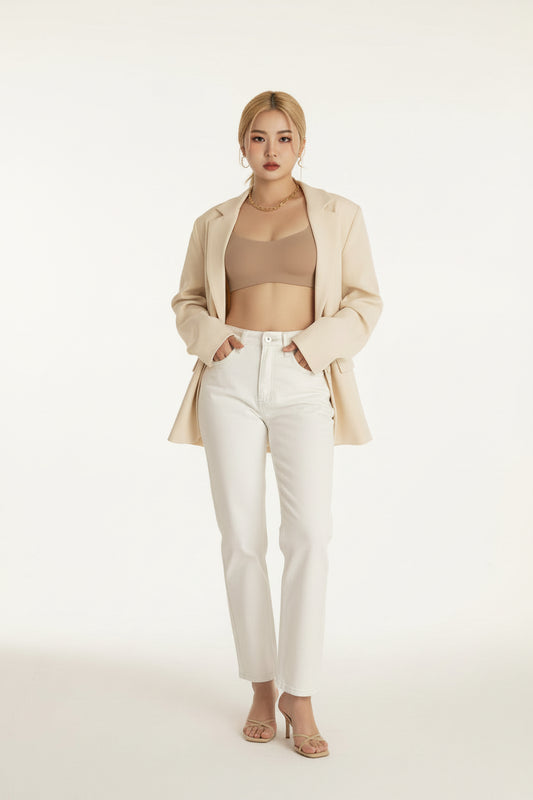Person wearing a beige bralette and white pants with a neutral background