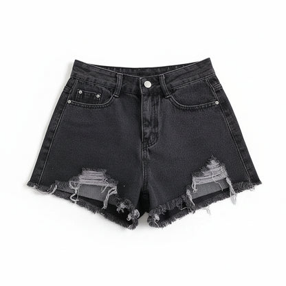 Black denim shorts with frayed edges on a white surface with a magazine.