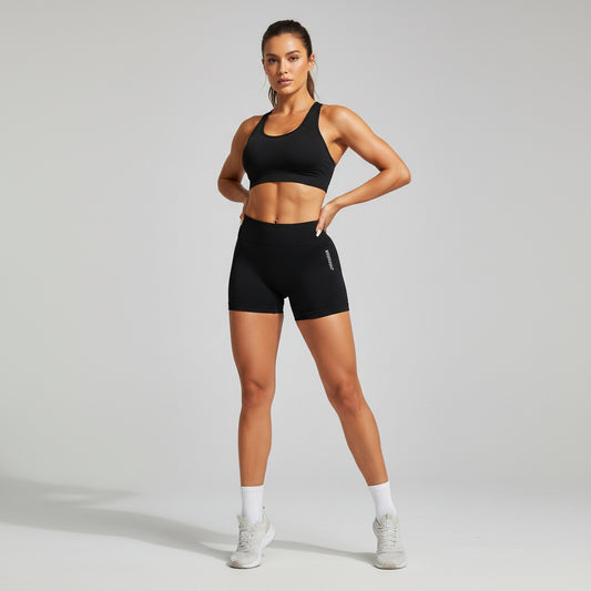 Black gym shorts with 'GYMWEAR' text on a person against a green plant background