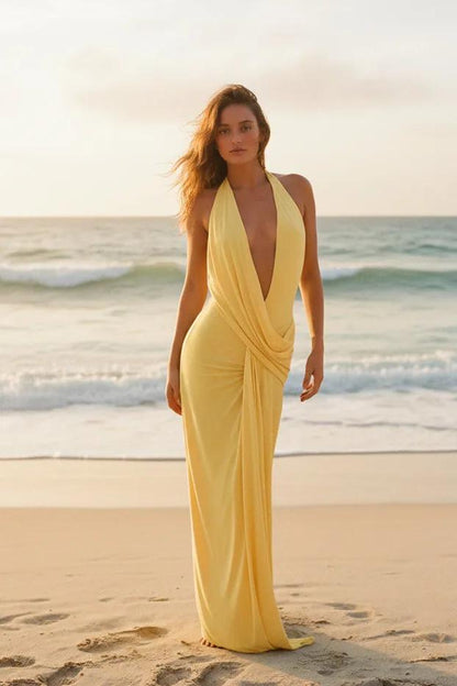 Woman in a yellow dress standing by a pool with greenery in the background
