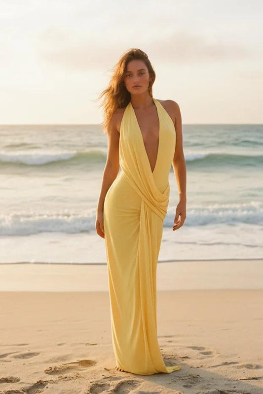 Woman in a yellow dress standing by a pool with greenery in the background
