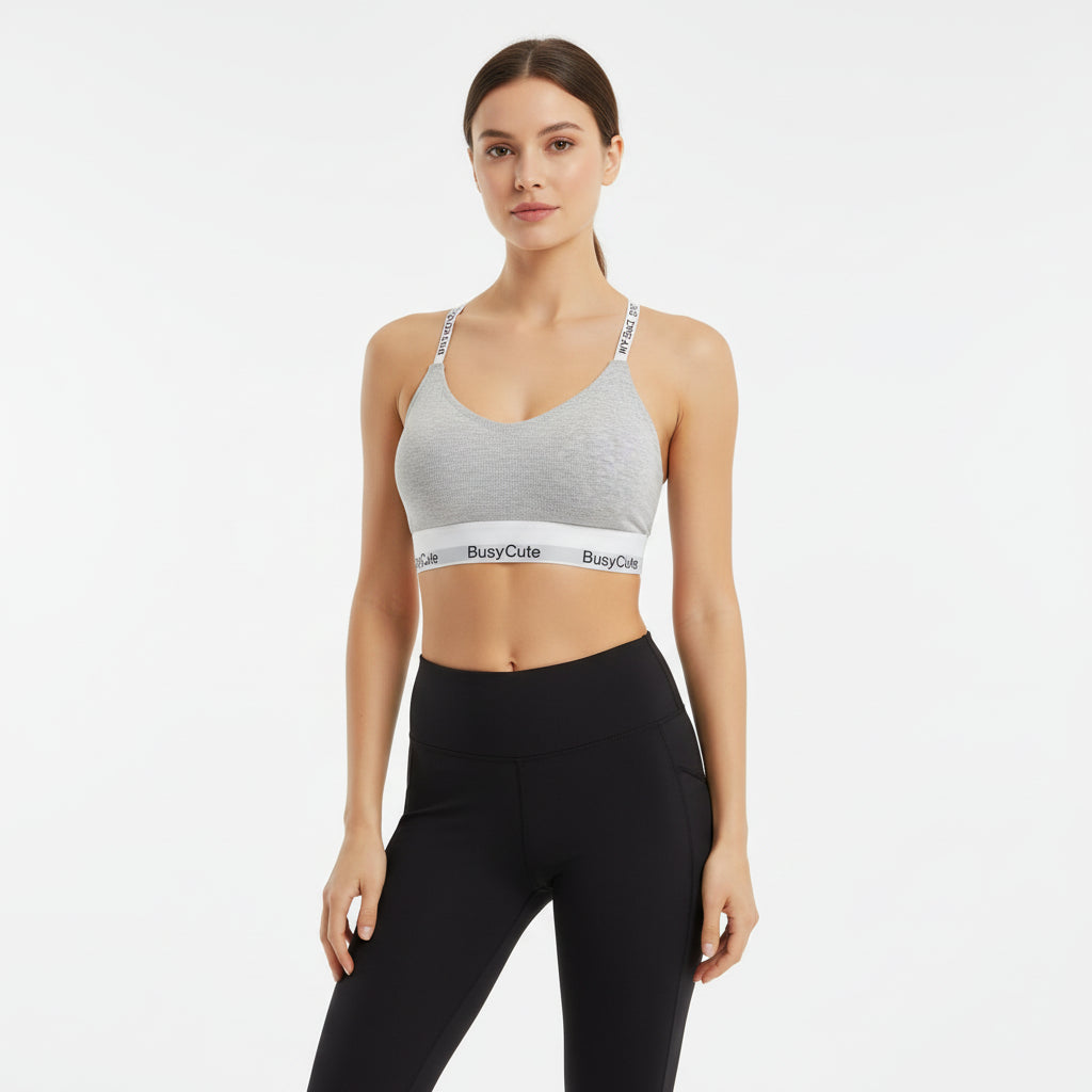 Gray bralette with 'Busy Cute' branding on a wooden surface with books in the background