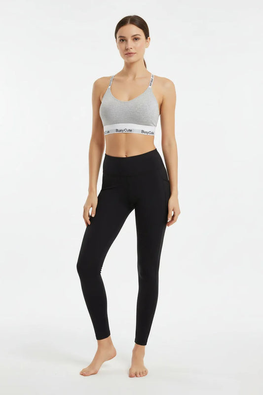 Gray bralette with 'Busy Cute' branding on a wooden surface with books in the background