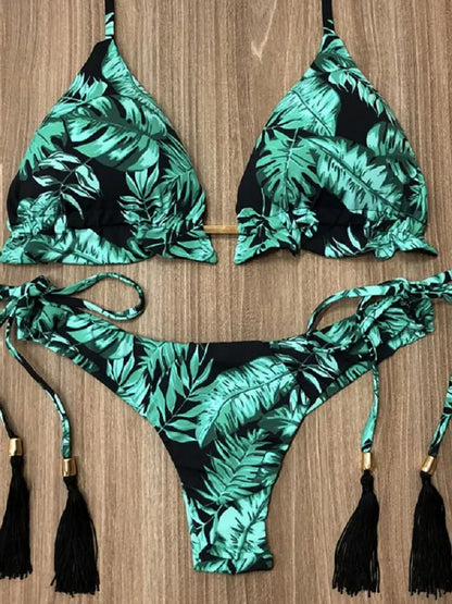 Green and black leaf-patterned bikini set on a wooden surface