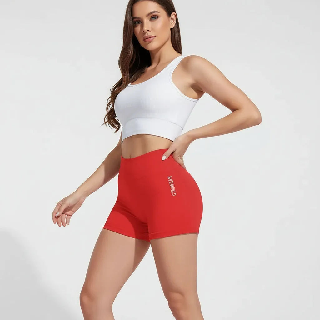 Red gym shorts with 'Gymwear' text worn by a person, blurred background