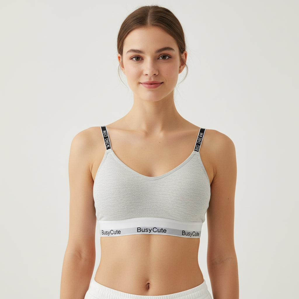 Gray bra with 'Busy Cute' band on a wooden coaster with books in the background
