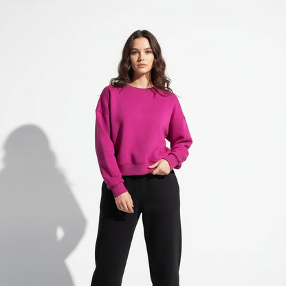 Person wearing a bright pink hoodie and black pants against a white background