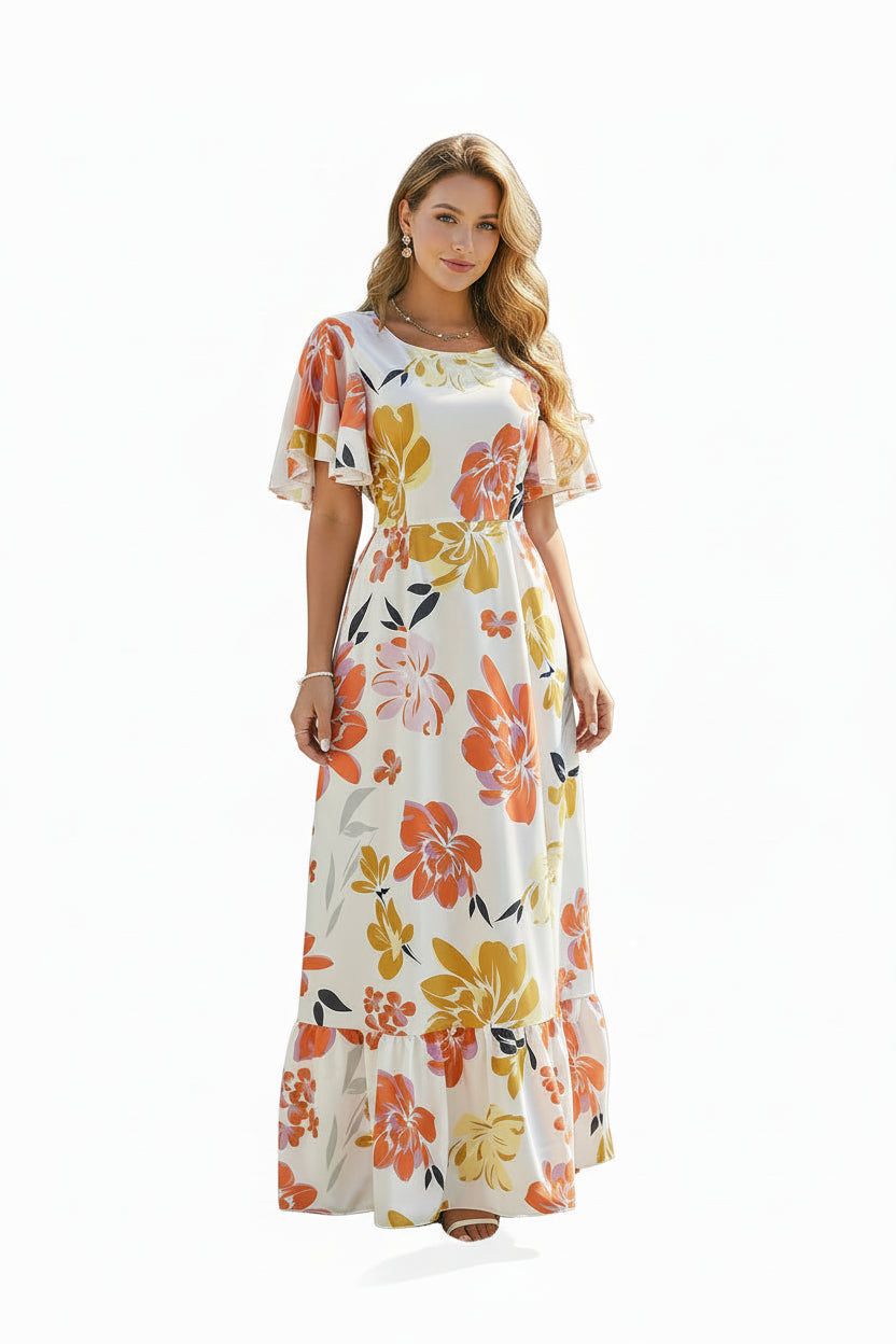Woman in a floral dress standing by a white fence with flowers in a garden.