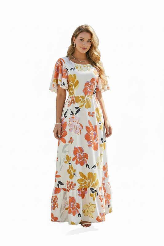Woman in a floral dress standing by a white fence with flowers in a garden.