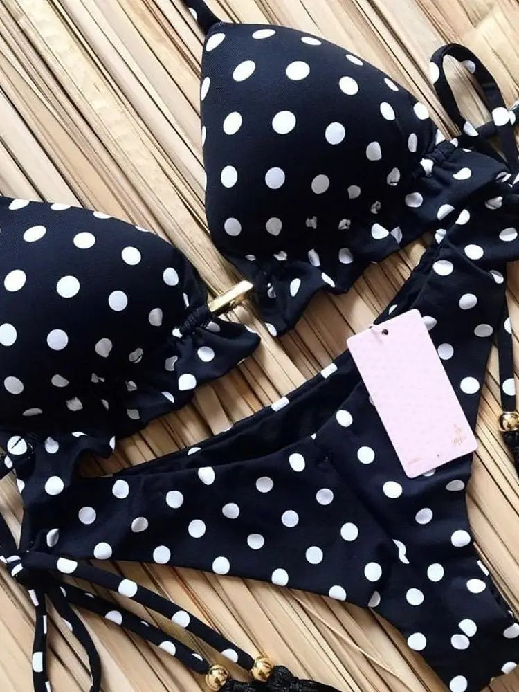 Black polka dot bikini set with a tag on a wooden surface