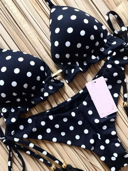 Black polka dot bikini set with a tag on a wooden surface